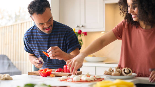 A man and a support worker preparing a meal together, chopping vegetables in a kitchen